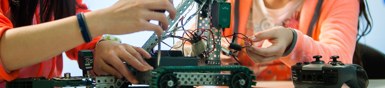 two girls work on a robot 